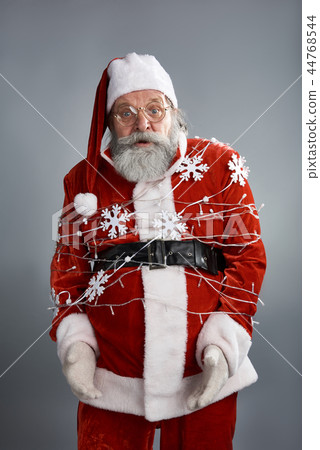 Santa Claus tied up with christmas light standing on gray background 44768544
