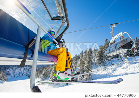 Skier sitting at ski chair lift. 44770900