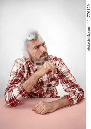 Handsome hipster man smoking cigarette at home. Man looking upwards and enjoying spending free time. Handsome hipster man smoking cigarette at home. Man looking upwards and enjoying spending free time. 44776199