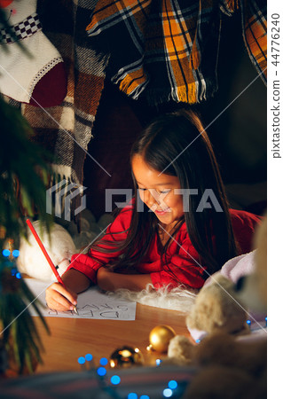 Merry Christmas and Happy Holidays. Cute little child girl writes the letter to Santa Claus near Merry Christmas and Happy Holidays. Cute little child girl writes the letter to Santa Claus near 44776240