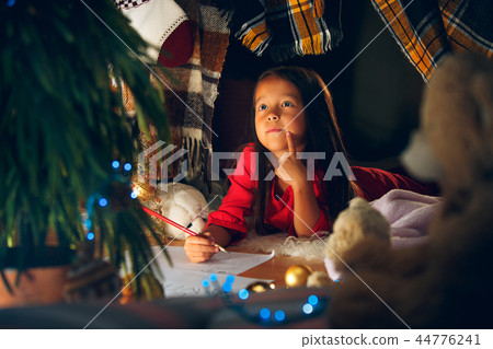 Merry Christmas and Happy Holidays. Cute little child girl writes the letter to Santa Claus near Merry Christmas and Happy Holidays. Cute little child girl writes the letter to Santa Claus near 44776241