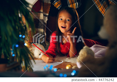 Merry Christmas and Happy Holidays. Cute little child girl writes the letter to Santa Claus near Merry Christmas and Happy Holidays. Cute little child girl writes the letter to Santa Claus near 44776242