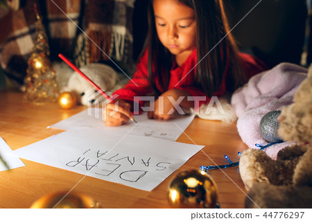 Merry Christmas and Happy Holidays. Cute little child girl writes the letter to Santa Claus near Merry Christmas and Happy Holidays. Cute little child girl writes the letter to Santa Claus near 44776297