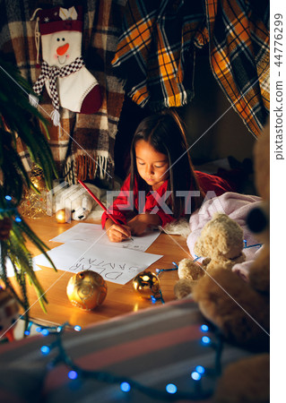 Merry Christmas and Happy Holidays. Cute little child girl writes the letter to Santa Claus near Merry Christmas and Happy Holidays. Cute little child girl writes the letter to Santa Claus near 44776299