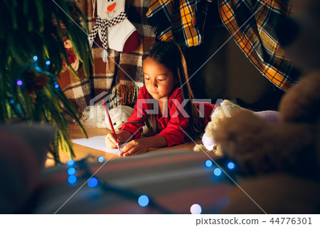Merry Christmas and Happy Holidays. Cute little child girl writes the letter to Santa Claus near Merry Christmas and Happy Holidays. Cute little child girl writes the letter to Santa Claus near 44776301
