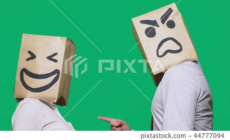 The concept of emotions and gestures. Two people in paper bags with smiles. Aggressive smiley swears The concept of emotions and gestures. Two people in paper bags with smiles. Aggressive smiley swears 44777094