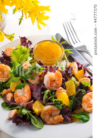 Healthy salad with prawns, lettuce, oranges and mango served on a plate with orange mustard sauce 44777370