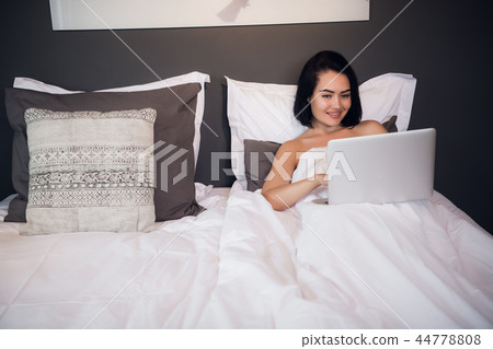 Portrait of beautiful young woman with laptop on bed 44778808