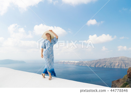young woman in a white and blue dress enjoys a walk around Santorini young woman in a white and blue dress enjoys a walk around Santorini 44778846