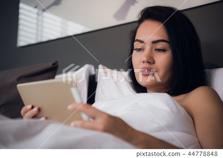 attractive brunette girl holding digital tablet with blank screen and smiling in bedroom attractive brunette girl holding digital tablet with blank screen and smiling in bedroom 44778848