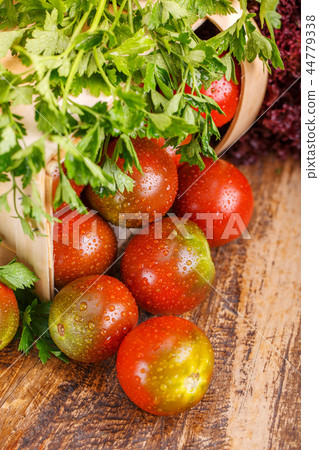 Parsley is on tomatoes on a wooden table 44779338