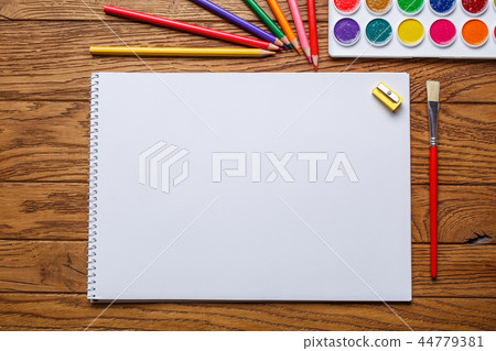 On the table there is an album for painting, paint and pencils 44779381