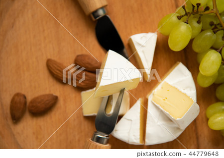 cheese camembert with raspberries and grapes on table 44779648