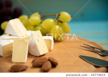 cheese camembert with raspberries and grapes on table 44779654