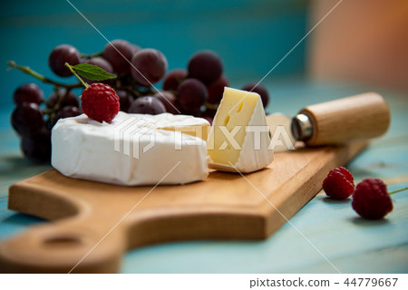 cheese camembert with raspberries and grapes on table 44779667