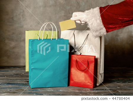 Santas hand holding a plastic card against grey background Santas hand holding a plastic card against grey background 44780404