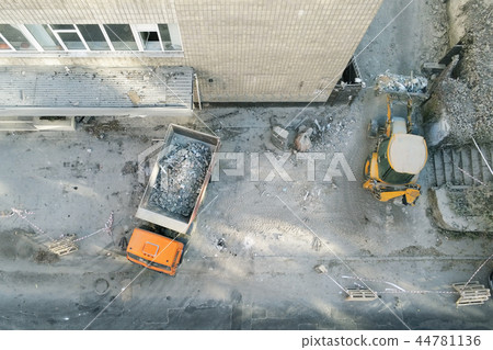 Bulldozer loader uploading waste and debris into dump truck at construction site. building 44781136