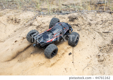 Big radio controlled buggy car driving fast and slipping on sand. RC toy moving fast on cross Big radio controlled buggy car driving fast and slipping on sand. RC toy moving fast on cross 44781162