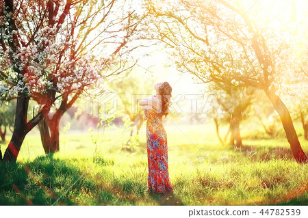 light portrait of an apple tree, girl portrait of a high key, spring mood freshness and purity blonde with long hair in a blooming park in the spring 44782539