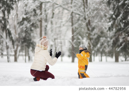 Boy and mother playing snowballs in winter Park. 44782956
