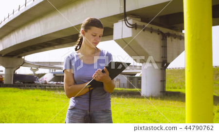 Woman ecologist standing near higway and writing something 44790762