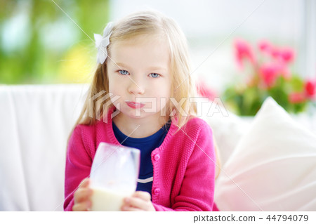 Cute little girl drinking fresh organic milk at sunny summer day. Healthy nutrition for children. Cute little girl drinking fresh organic milk at sunny summer day. Healthy nutrition for children. 44794079