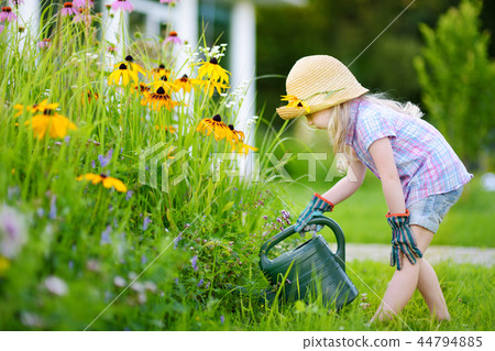 Cute little girl watering flowers in the garden Cute little girl watering flowers in the garden 44794885