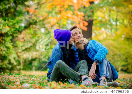 Young couple sitting on ground in a autumn season time park Young couple sitting on ground in a autumn season time park 44796206