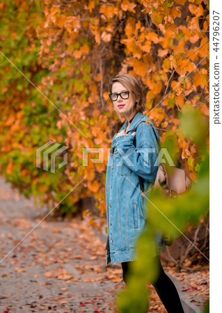 girl in glasses and jacket in a autumn season park.  44796207