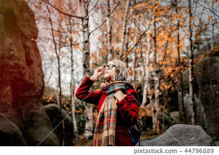 girl in scarf and coat in a forest with rocks girl in scarf and coat in a forest with rocks 44796889