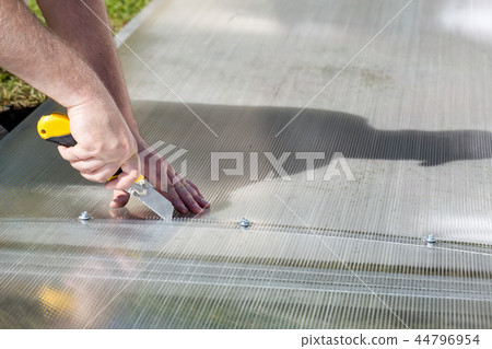 Worker cutting polycarbonate with knife 44796954