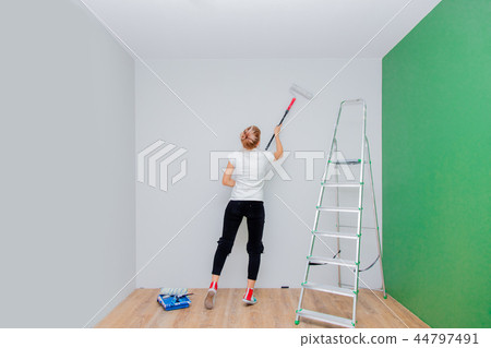 woman with paint roller and ladder in own house  44797491