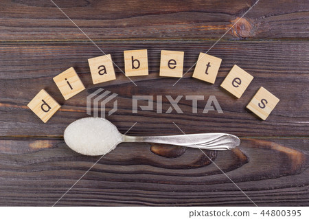 Diabetes block wood and sugar pile on a spoon Diabetes block wood and sugar pile on a spoon 44800395