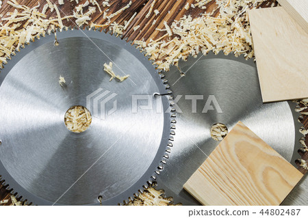 Two saw blades and pieces of wood on sawdust Two saw blades and pieces of wood on sawdust 44802487