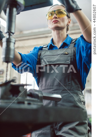 Woman worker in metal workshop using pedestal drill 44802607