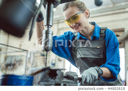 Woman worker in metal workshop using pedestal drill 44802618