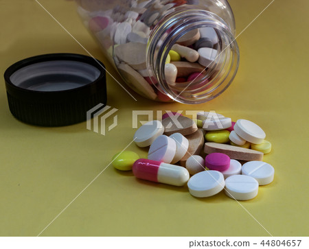 different pills from a bottle on a yellow background different pills from a bottle on a yellow background 44804657
