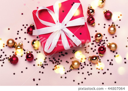 Christmas gift box and balls with confetti on pink background Christmas gift box and balls with confetti on pink background 44807064