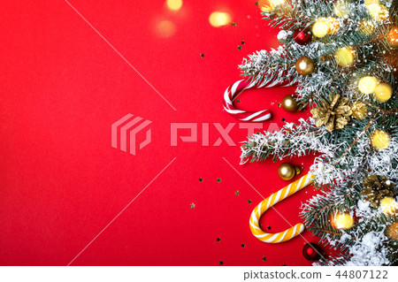 Red Christmas background with coniferous border. Candy canes and glowing lights Red Christmas background with coniferous border. Candy canes and glowing lights 44807122
