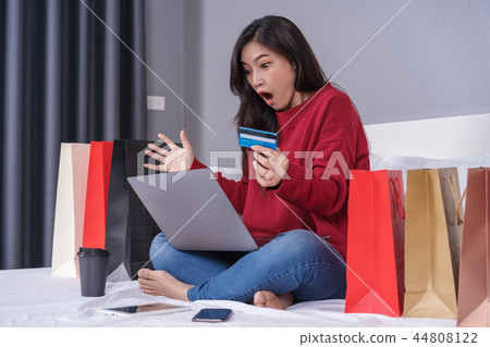 shocked woman using laptop for online shopping with credit card 44808122