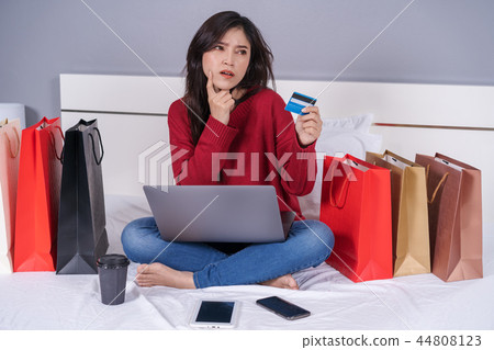 woman thinking and using laptop computer for online shopping wit 44808123