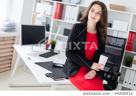A young girl sat down on a table in the office and holding a glass of coffee. A young girl sat down on a table in the office and holding a glass of coffee. 44808912