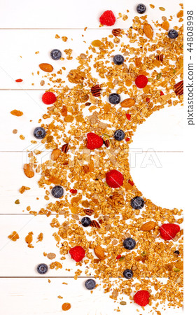 Scattered granola, nuts and berries on white wood background. Scattered granola, nuts and berries on white wood background. 44808998