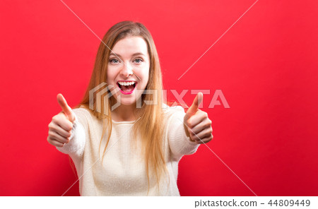 Happy young woman giving thumbs up Happy young woman giving thumbs up 44809449