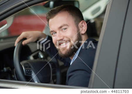 Driver looking at camera from car cabin and smiling. 44811703