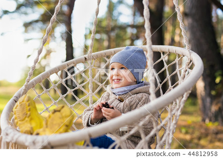 Cute kid swinging in a hanging chair in a forest Cute kid swinging in a hanging chair in a forest 44812958