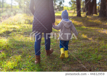 Young mother holding her kid's hand while walking in the forest Young mother holding her kid's hand while walking in the forest 44812959