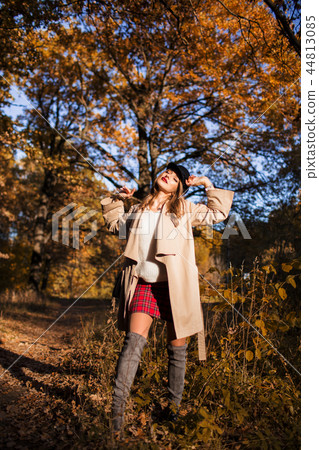 Pretty stylish woman with fashion makeup in autumn park is wearing hat and coat 44813085