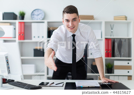 The young man in the office stands up and stretches his hand forward. The young man in the office stands up and stretches his hand forward. 44815627