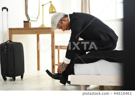 Business trip romance gray businessman tying shoelace in hotel room 44818461